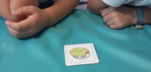 Bild: Kinderhände mit 1 Karte mit Froschgesicht