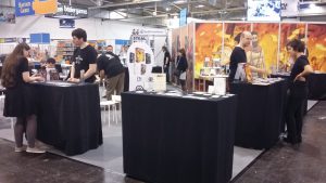 Bild: Messestand an dem Besuchern neue Spiele präsentiert werden