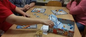 Bild: Spieler am Tisch sitzend mit Spielmaterial