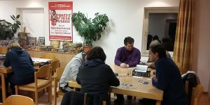 Bild: Spieler sitzen an Tischen