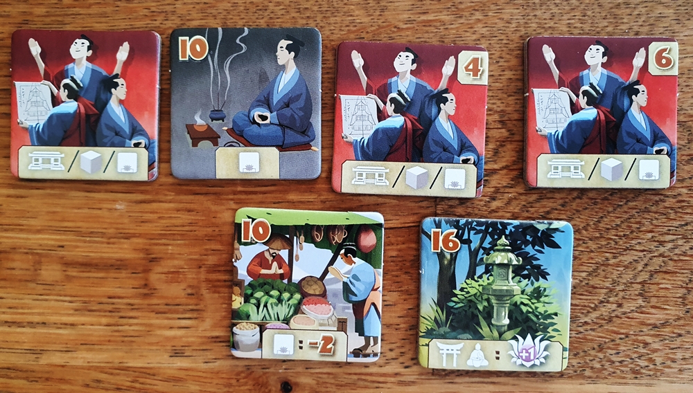 In der oberen Reihe vier Aktionsplättchen, eines ist zugekauft. In der unteren Reihe zwei Vorteilsplättchen