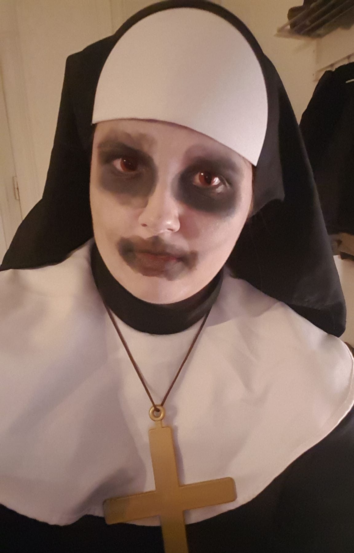Zu sehen ist eine weiß geschminkte Frau mit roten Kontaktlinsen, die eine Vampir-None darstellt. 