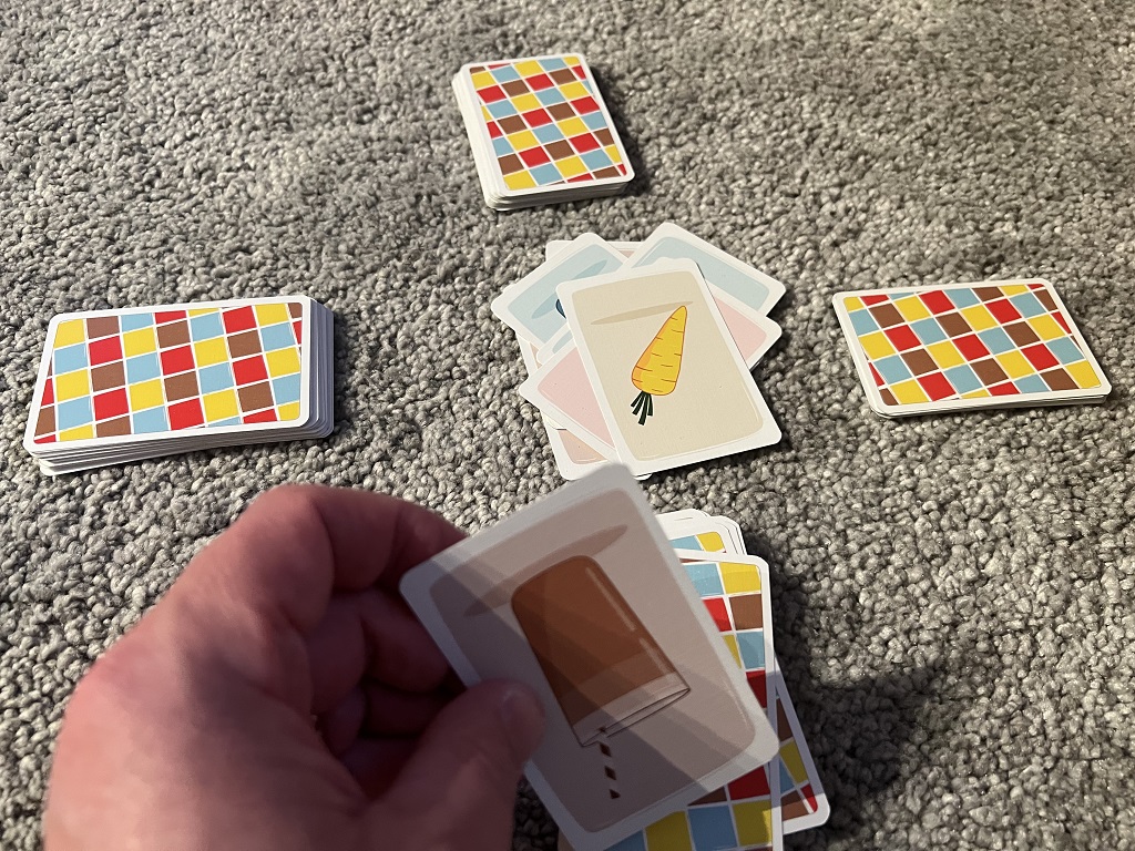 Spielaufbau für vier Spieler, in der Mitte liegt die gelbe Karotte die nicht genannt werden darf.