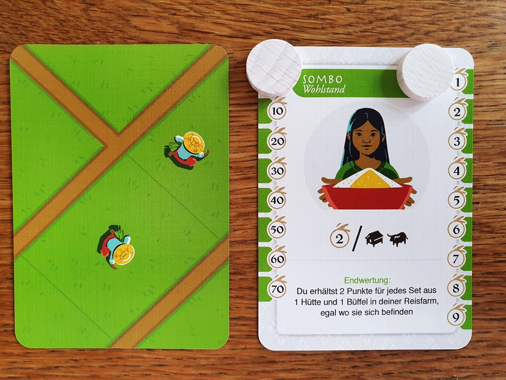 Zwei Karten bilden die Startauslage: eine als Beginn des Reisfeldes, eine umgedreht mit Zusatz-Siegbedingungen und als Zählleiste, darauf zwei Marker für Einser und Zehnerstellen