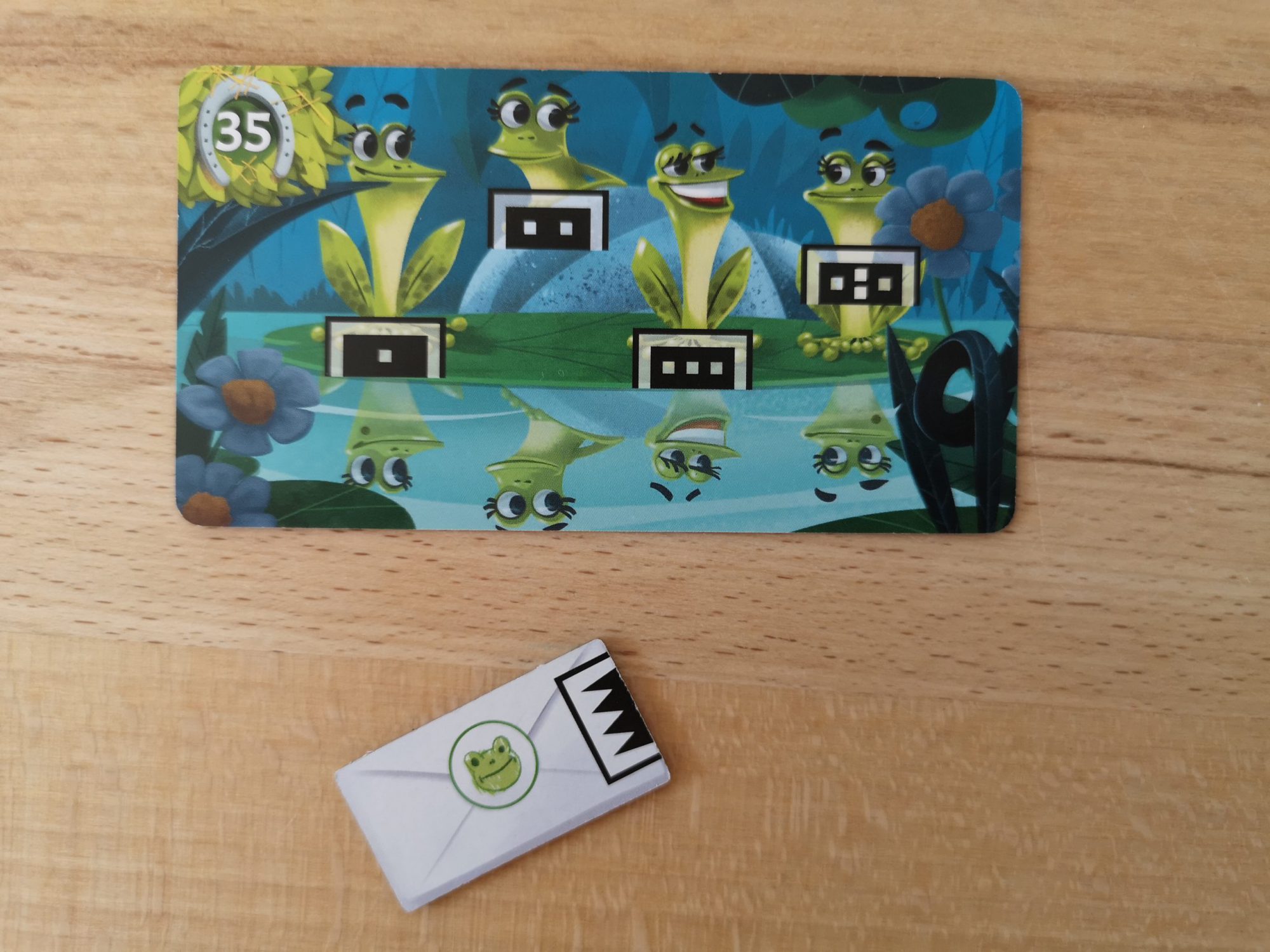 Ein Brief-Plättchen muss der richtigen Froschzeichnung auf einer Spielkarte zugewiesen werden.