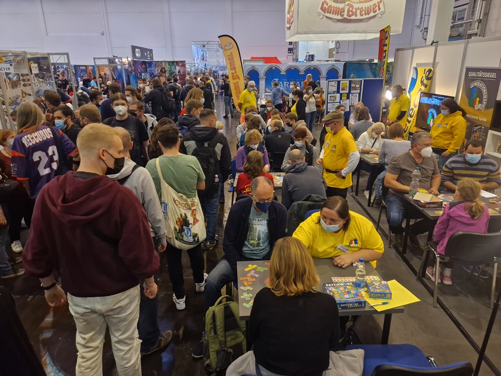 Messestand und viele Menschen am Stand und auf dem Gang