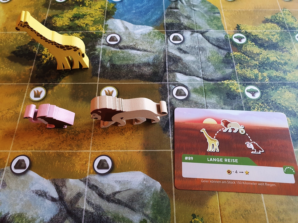 Aktionskarte und die Tiere auf dem Spielplan, die den Auftrag erfüllen