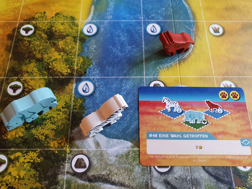 Aktionskarte und die Tiere auf dem Spielplan, die den Auftrag erfüllen