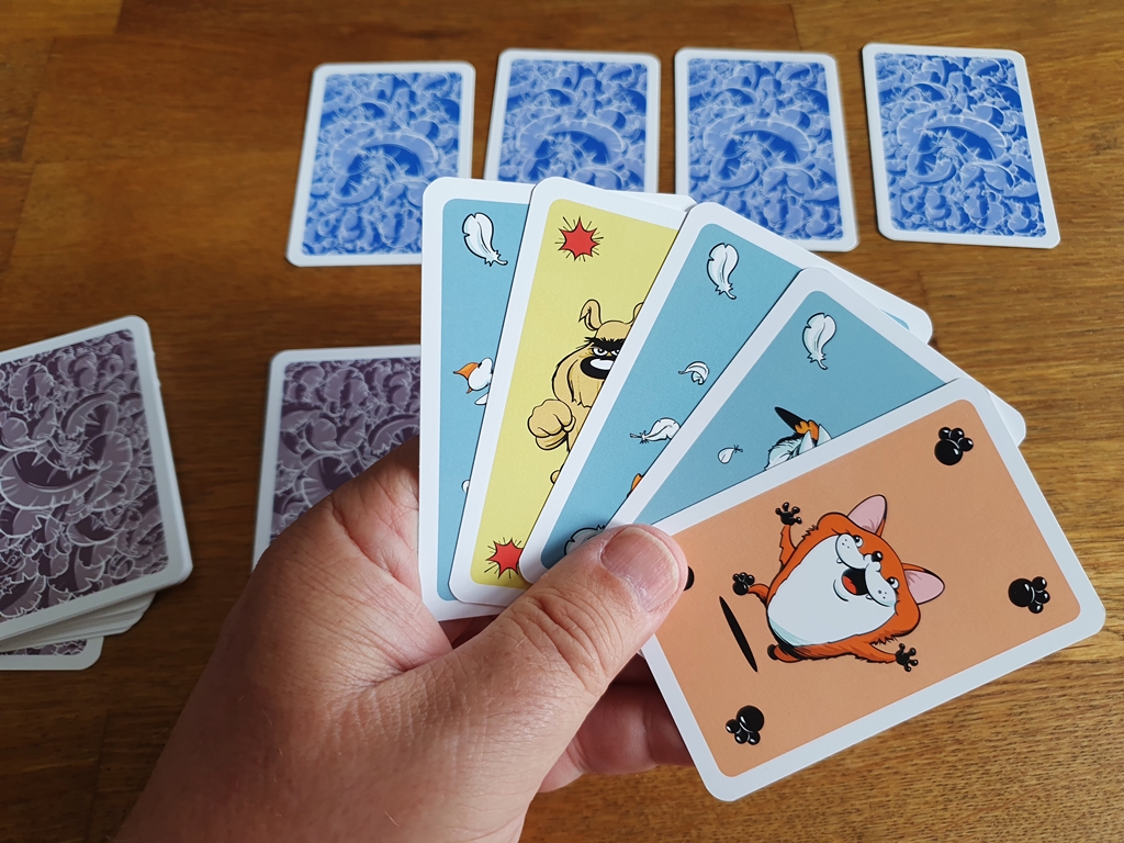 Kartenhand mit fünf Karten. Auf dem Tisch die Auslage eines Mitspielenden