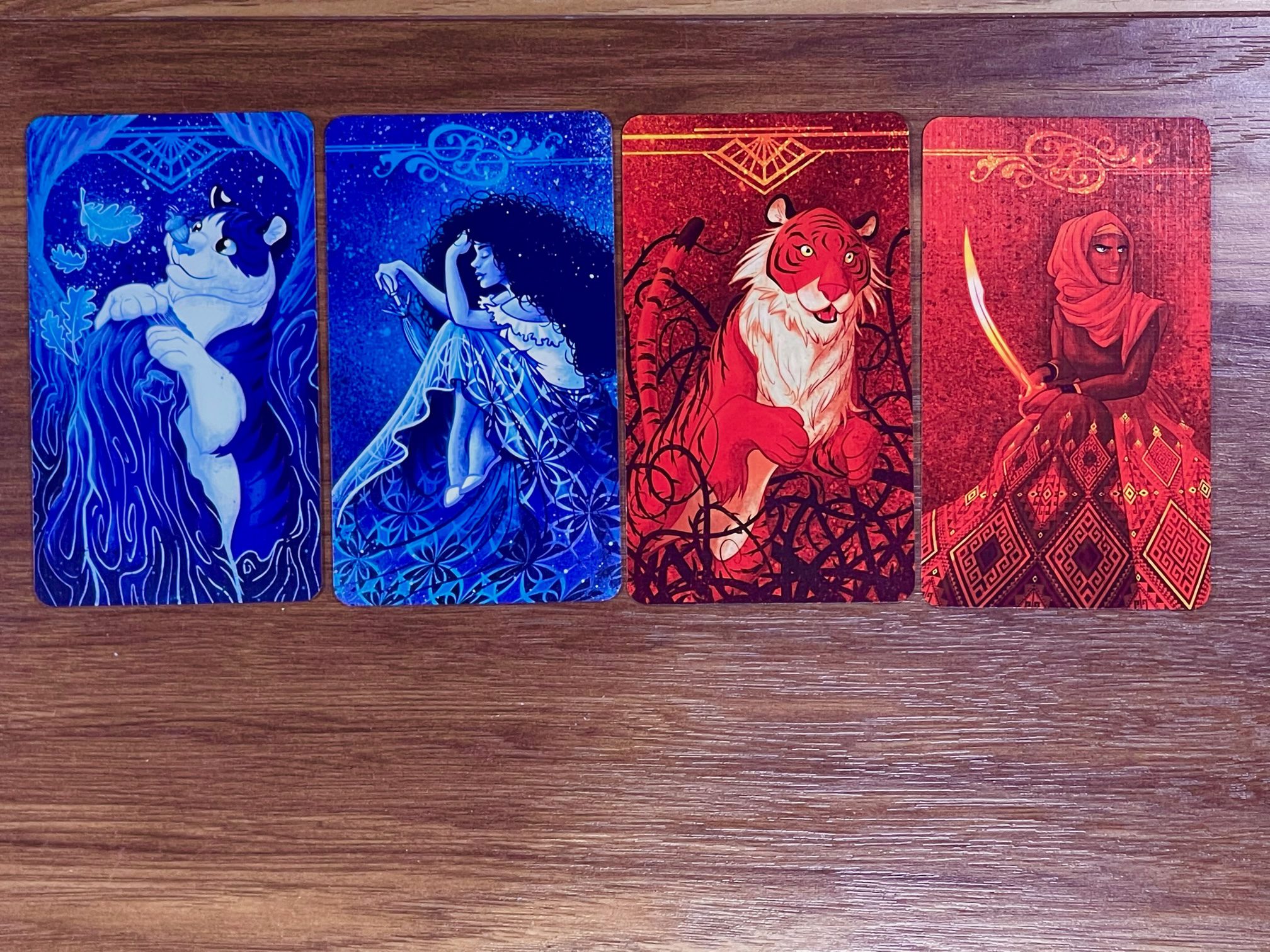 Auf dem Bild sind vier verschiedene Karten abgebildet. Zwei in rot und zwei in blau. Zwei der Karten, eine blaue und eine rote, zeigen einen Tiger und zwei der Karten zeigen eine Dame.