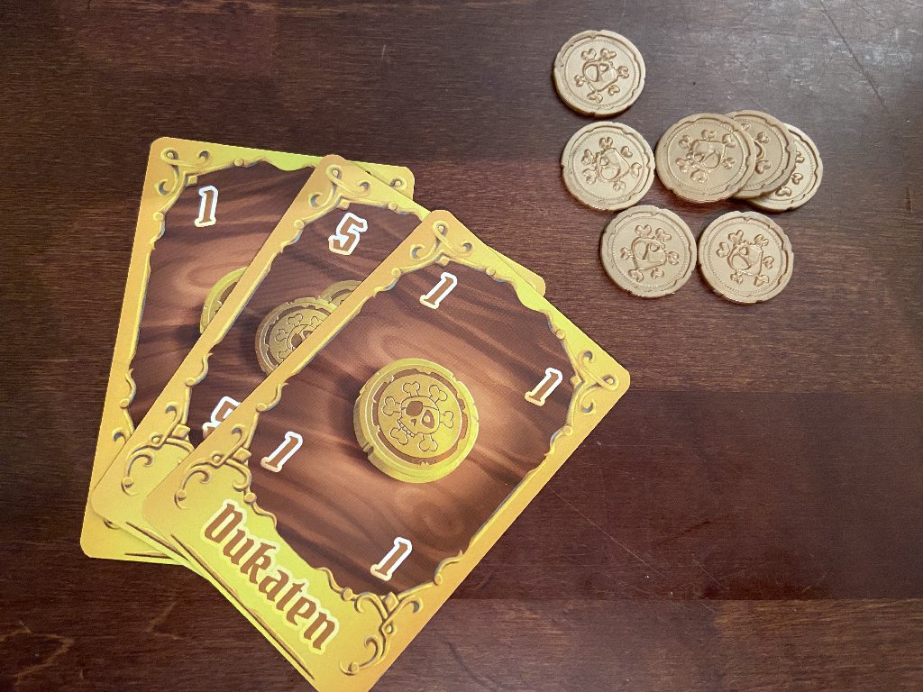 Karten mit Golddublonen und Plastikdublonen in gleich Anzahl daneben