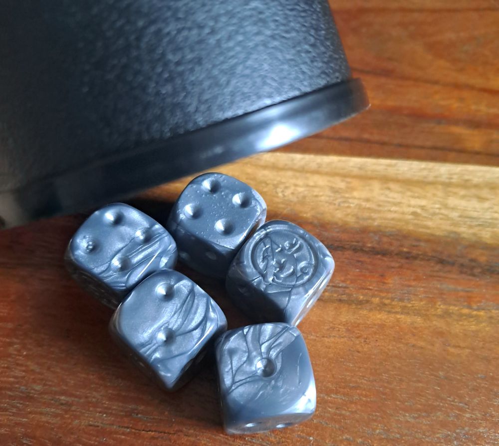 Fünf Würfel unter angehobenem Würfelbecher