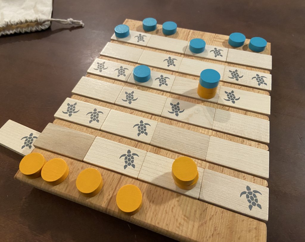 Das Spiel ist im Gange. Ein paar Spielsteine liegen noch am Rand, ein paar sind schon auf den Holzplättchen gestapelt.