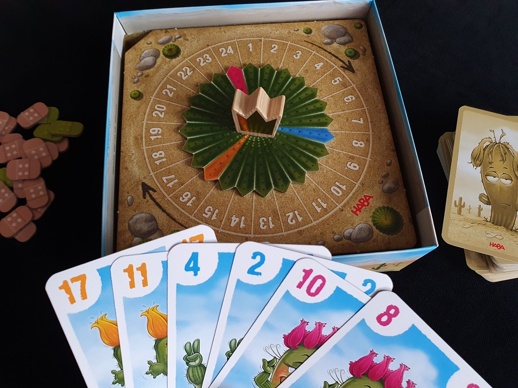 Im Spielkarton ist ein Drehrad integriert, das in drei Farbsegmenten auf Zahlen zwischen 1 und 24 zeigt