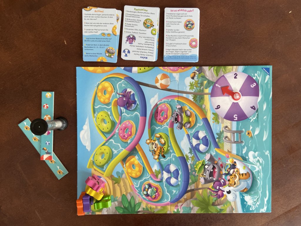 Spielbrett in der Mitte und Karten daneben. Die Spielfiguren stehen links oben auf dem Startfeld.