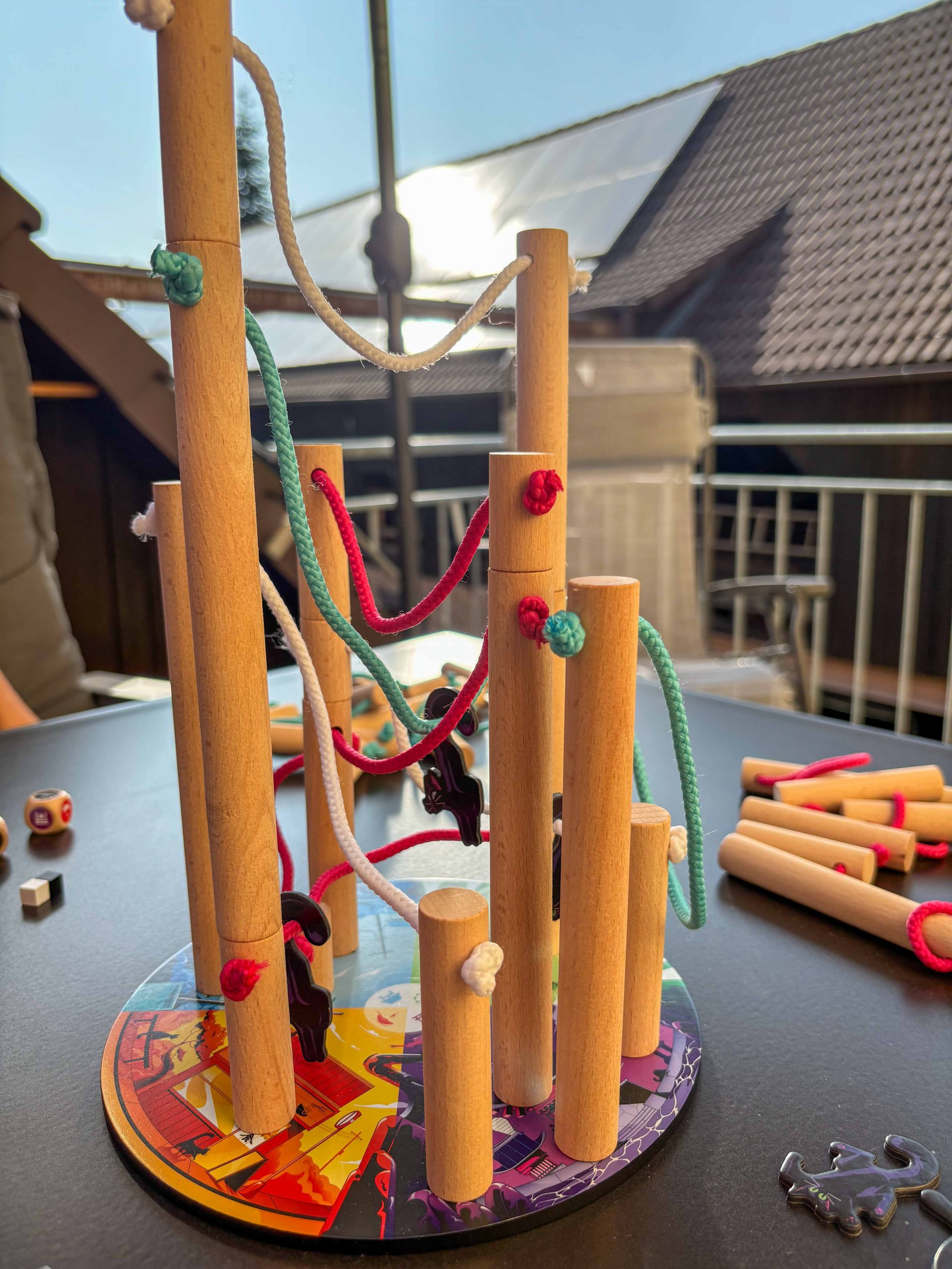 Aufeinandergestapelte Holzstäbe verbunden mit bunten Seilen