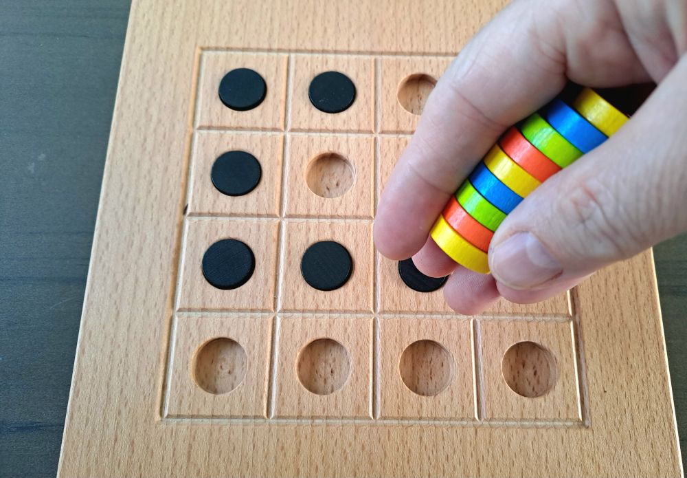 Zu sehen sind die in der Hand gestapelten Spielsteine über dem Spielbrett.