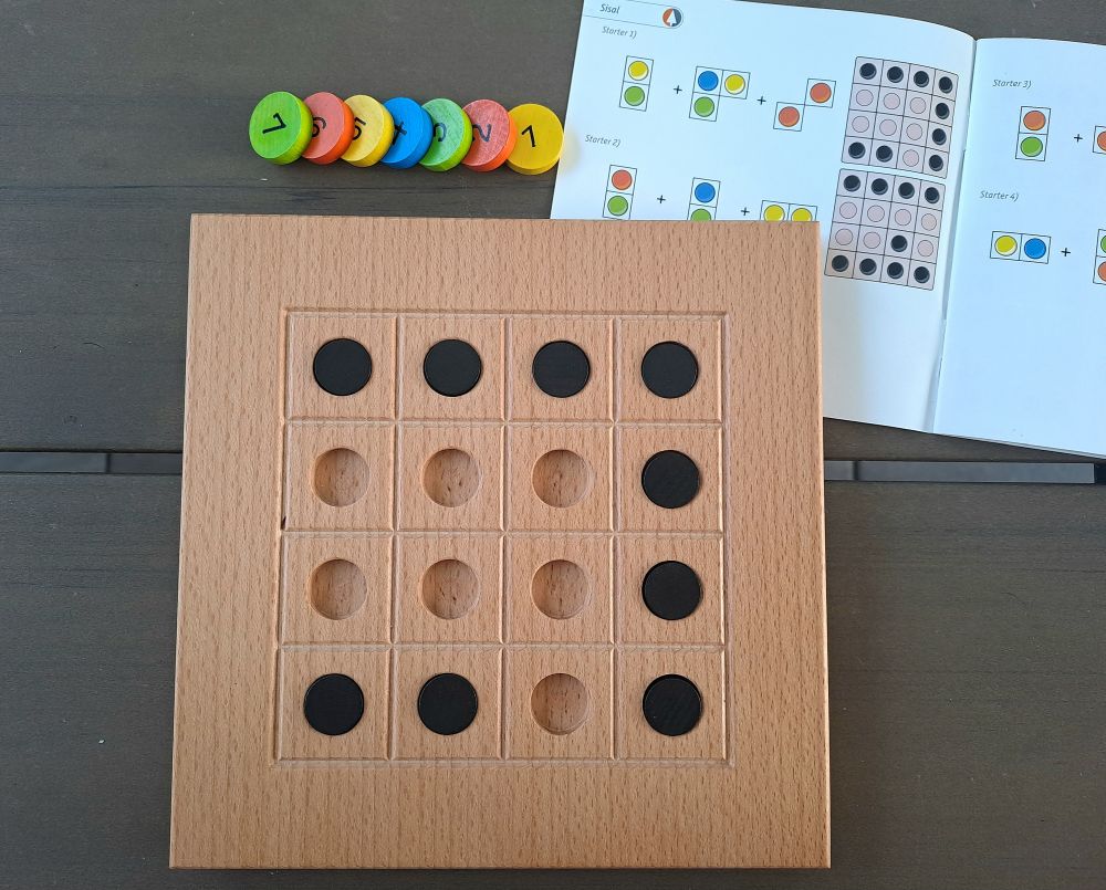 Zu sehen ist das Spielbrett sowie alle nötigen Holzplättchen. Das Aufgabenheft ist aufgeschlagen und zeigt die zu lösende Aufgabe. 
