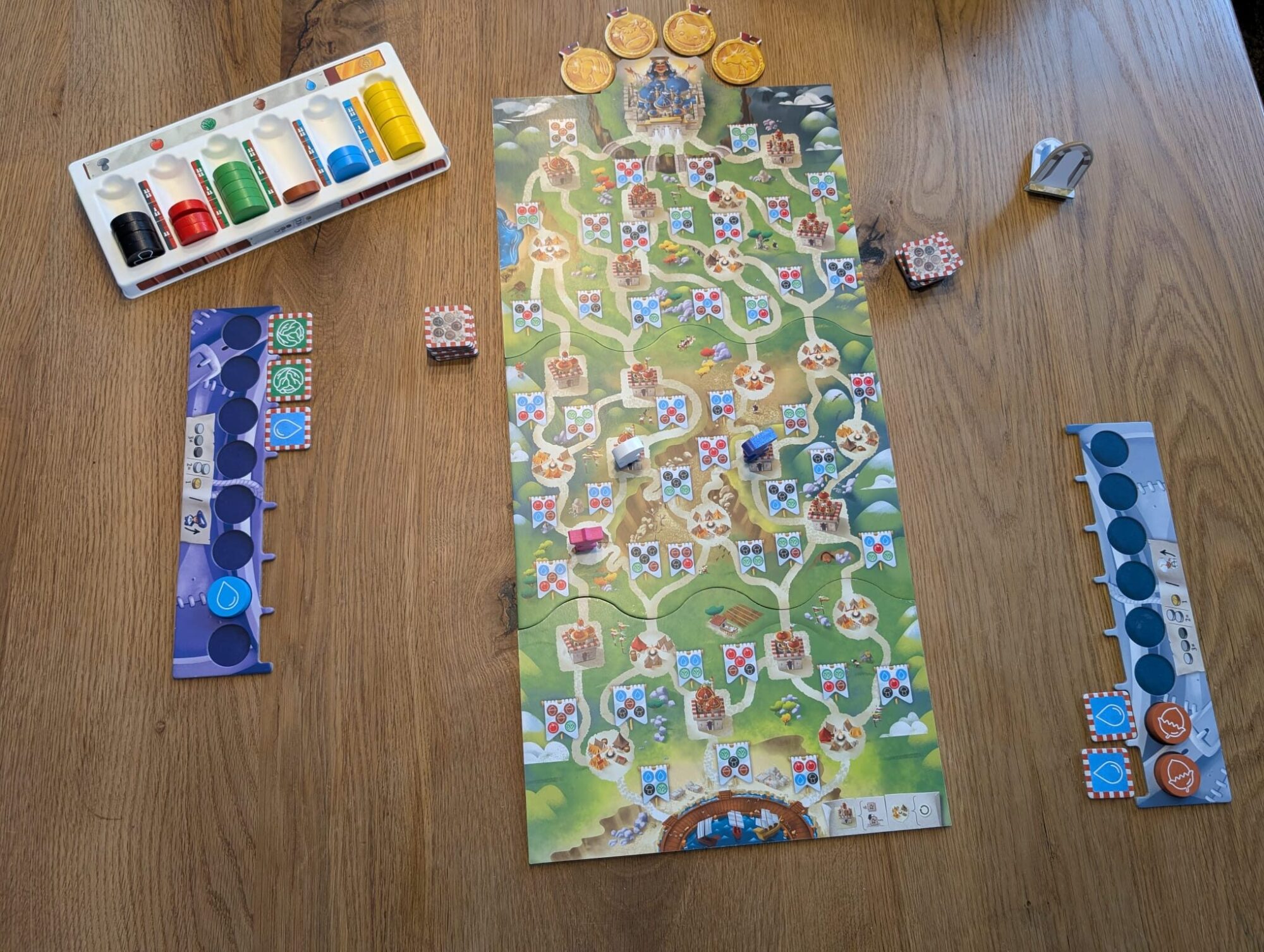 Auf dem Foto ist ein Auszug des Spiels zu sehen. Die Figuren befinden sich mitten auf dem Weg, die Ressourcen liegen bereit und es wurden bereits einige Stadtplättchen aufgedeckt.