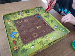 Auf dem Foto gießt ein Kind vom Rand aus. Man sieht, wie die Wasserkugel auf die Spielfläche rollt.