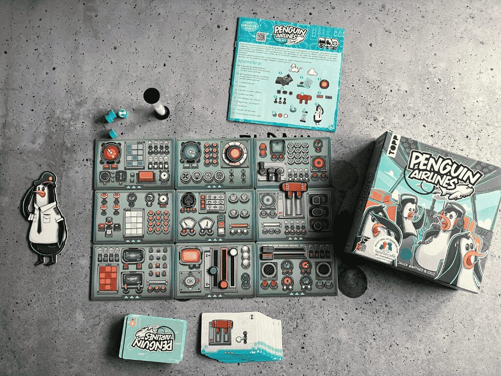 Penguin Airlines: Das Spielmaterial auf dem Tisch ausgebreitet - 12 Bedienfelder, Karten und eine Sanduhr.