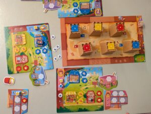 Auf dem Foto ist das Spiel der drei Mitspielenden zu sehen. Der Spieler mit der lila Farbe hat gerade das Ziel erreicht und somit ist das Spiel beendet. Man sieht auf den einzelen Spielertableau den aktuellen Spielstand.