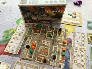 Spielszene. Der Spielplan bestehend aus vielen Karten sowie die Spielschachtel drauf gestellt.