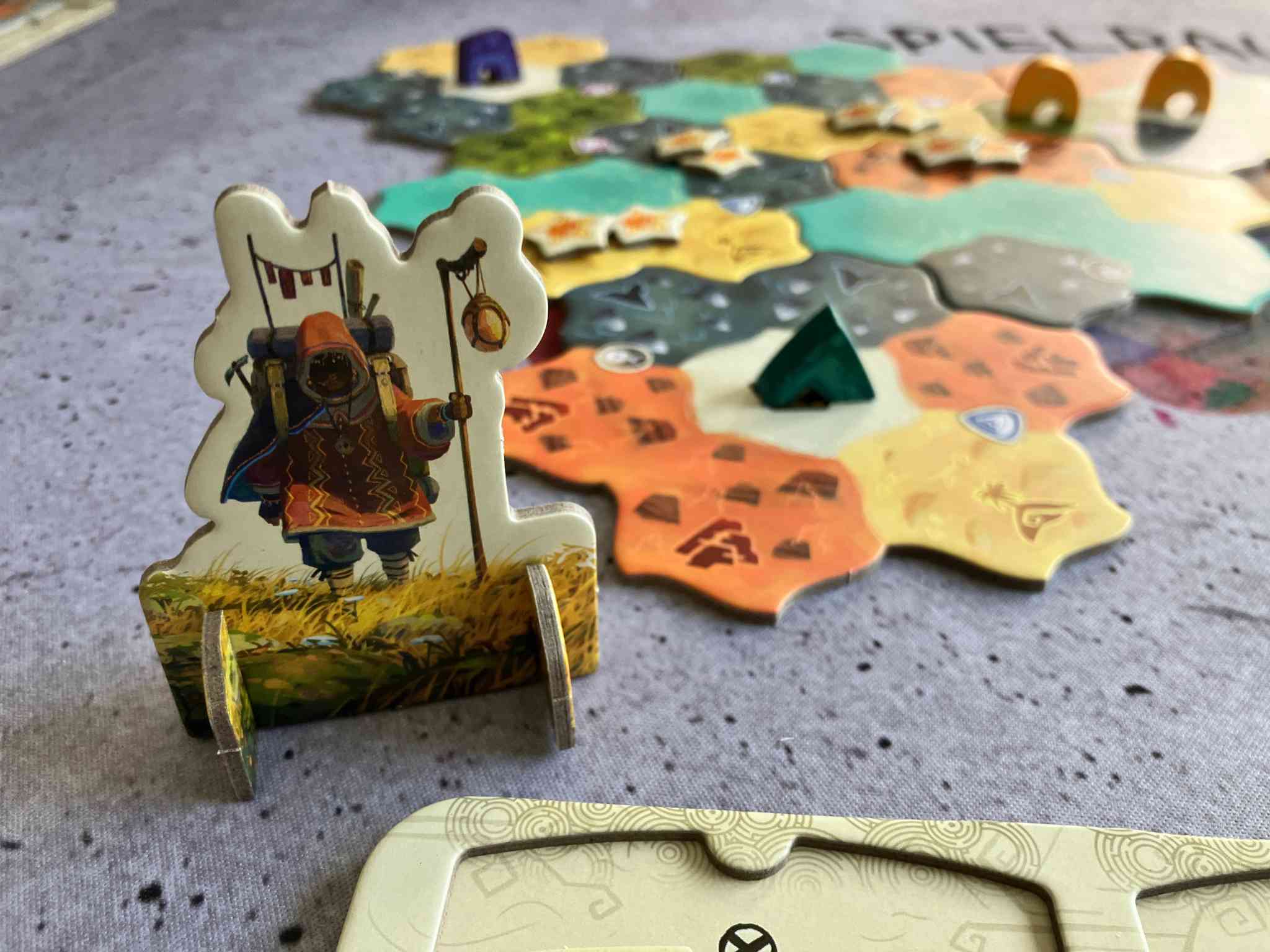 Dewan: Eine Aufstellerfigur markiert den Startspieler um bei Spielende allen die gleiche Anzahl an Zügen zu ermöglichen.