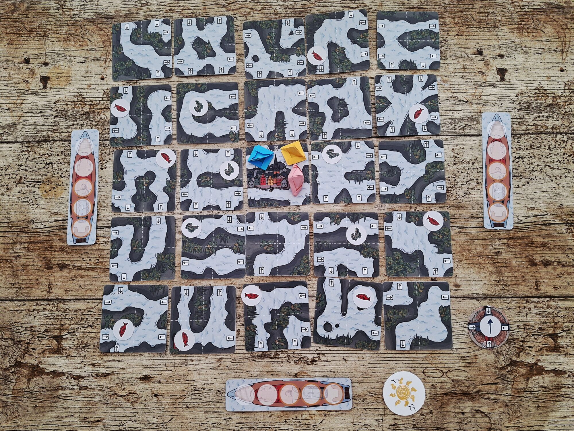Alle starten mit ihrem Boot in der Spielmitte. Auf den Kärtchen sind verschiedene Wege eingezeichnet. 